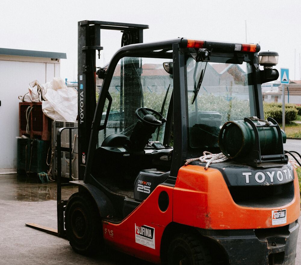 Red and black LPG counterbalance forklift parked outside a yard